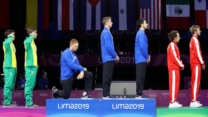 Il met un genou à terre sur le podium.