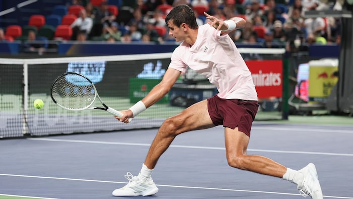 Il remet une balle du reverse, en glissant sur le court.