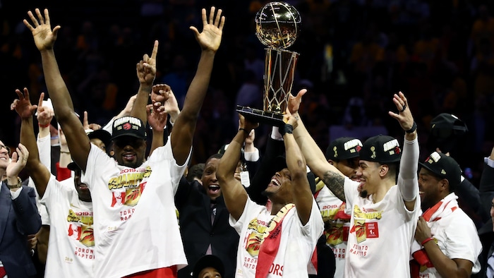 Des joueurs des Raptors lèvent les bras en signe de triomphe avec un trophée.