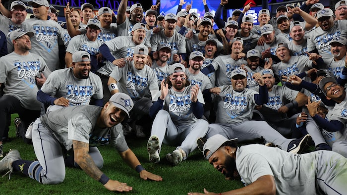 Des joueurs de baseball rassemblés et assis sur le terrain, célèbrent leur victoire.