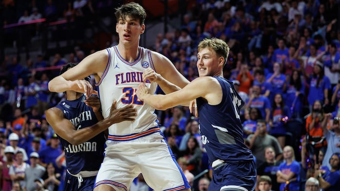 Un basketteur lutte avec deux joueurs.