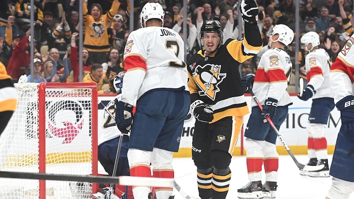 Un hockeyeur célèbre son but près de plusieurs adversaires.