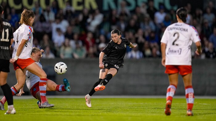 Lisa Pechersky frappe le ballon du pied gauche, devant deux joueuses des Roses de Montréal, lors d'un match à Vancouver. 