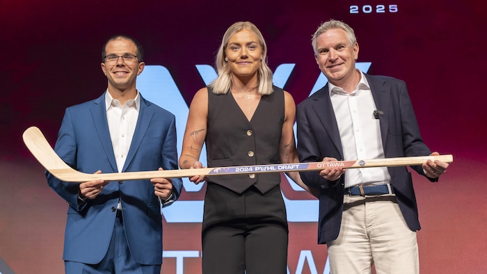 Une joueuse entourée de deux hommes tient un bâton. 