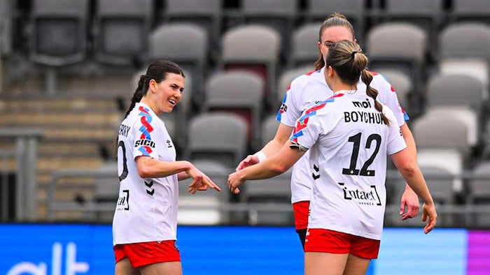 Trois joueuses de soccer se tapent les mains. 