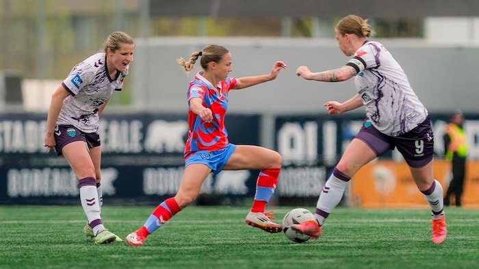 Une joueuse des Roses tente de contrôler le ballon, sous pression de deux adversaires des Tides.