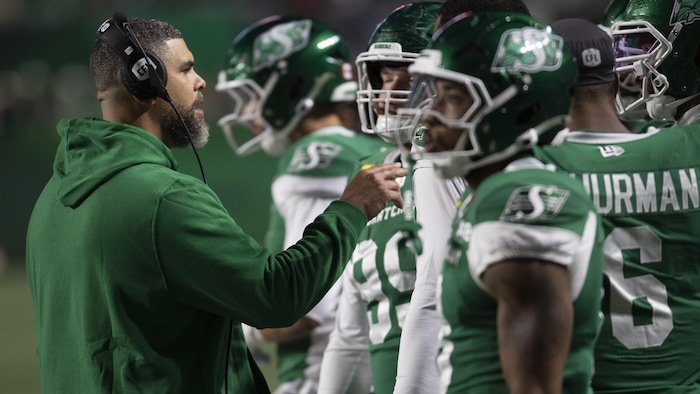 L'entraineur-chef des Roughriders Corey Mace donne des instructions à ses joueurs.