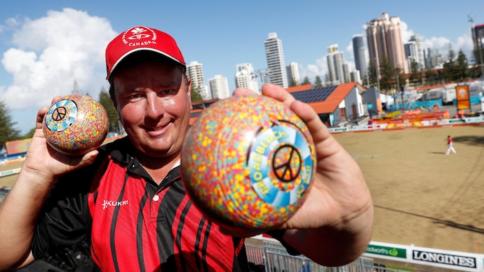 Un homme pose avec ses boules de boulingrin.