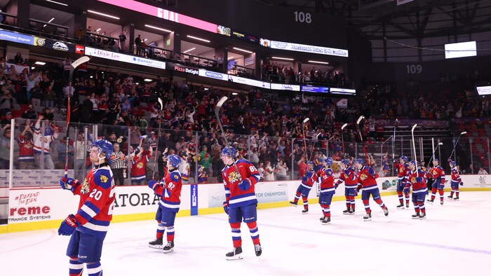 Joueurs soulevant leur bâton en signe de gratitude vers la foule.