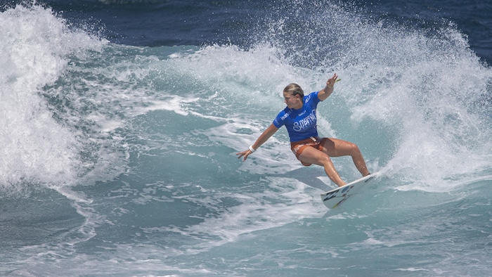 Une jeune femme sur une planche de surf en action sur une vague à Puerto Rico.