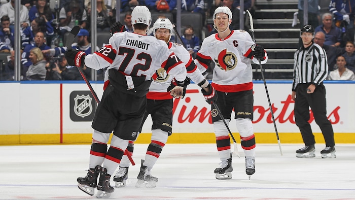 Trois coéquipiers au hockey célèbrent un but.