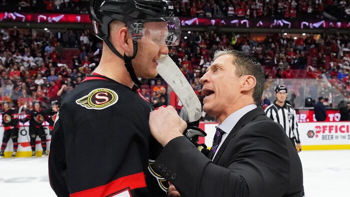 Un entraîneur félicite un joueur de hockey après avoir éliminé son équipe.