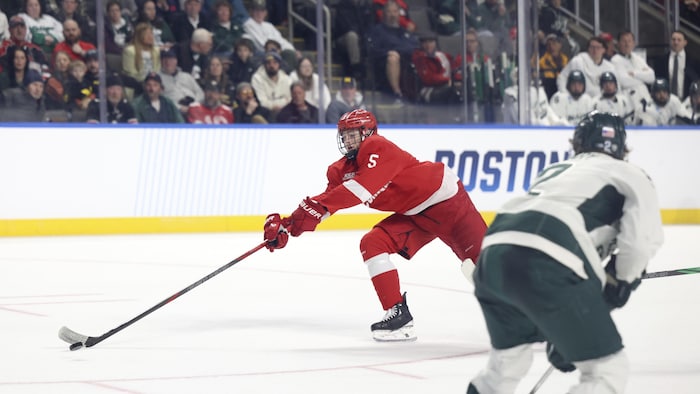 Un joueur de hockey étire le bras pour atteindre la rondelle dans un match. 