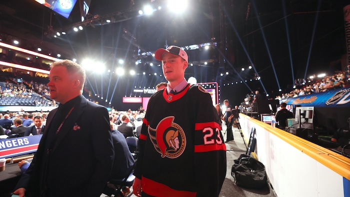 Un joueur de hockey patine vers une table lors de sa sélection au repêchage de la LNH.