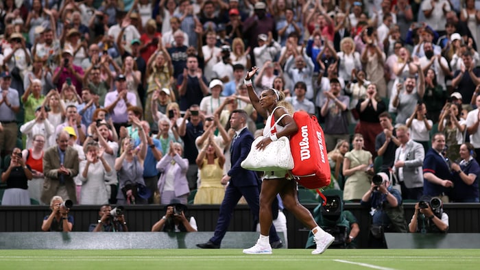 Une joueuse de tennis salue la foule à sa sortie du court.