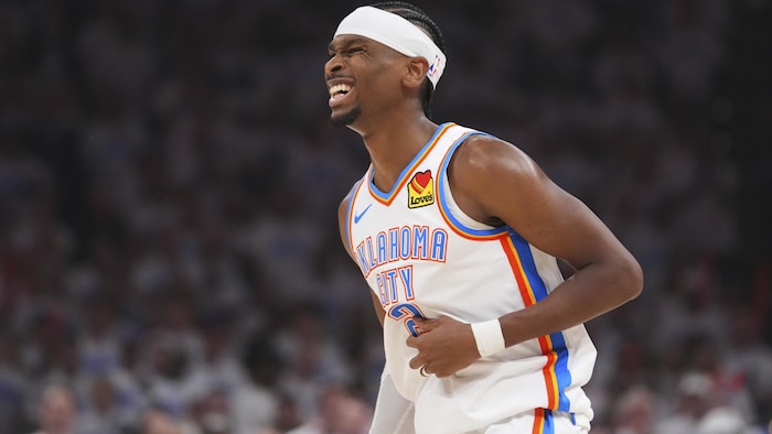Un joueur de basketball en blanc sourit après avoir marqué. 