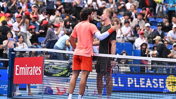 Deux joueurs de tennis se donnent la main au filet.