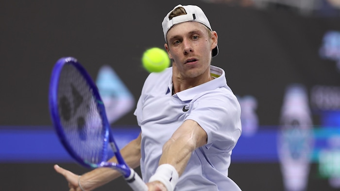 Un joueur de tennis frappe un revers.