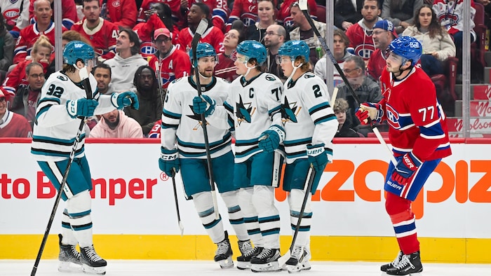 Des joueurs d'une équipe célèbrent un but devant un adversaire.