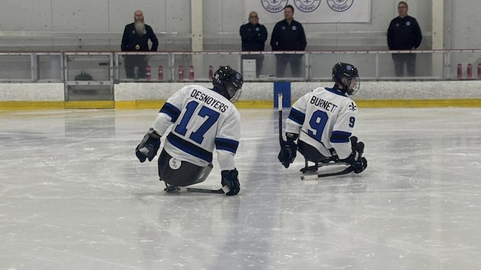 Deux hockeyeurs patinent sur leur luge lors d'un échauffemen.t