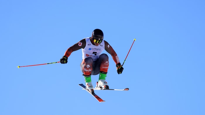 Le skieur est en plein vol lors d'une course de ski cross.