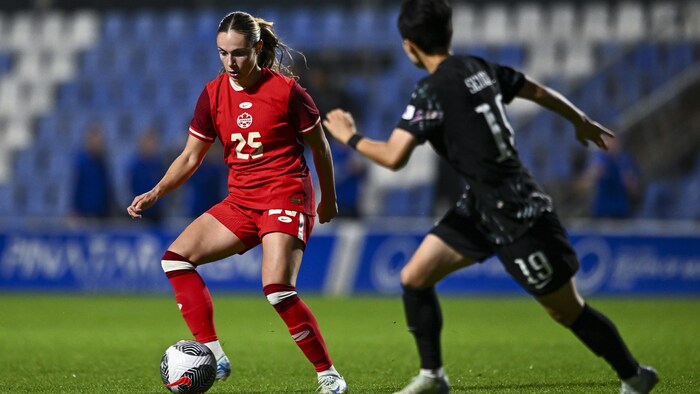 Elle tente de maîtriser le ballon devant une adversaire pendant un match du Canada contre la Corée du Sud.