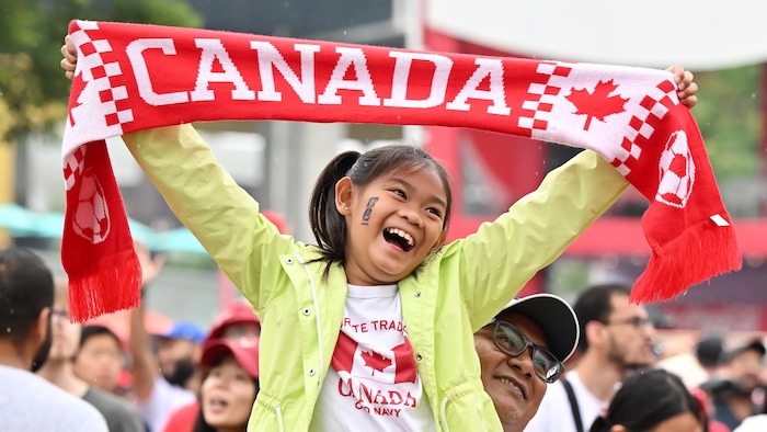Une petite fille brandit un foulard du Canada.
