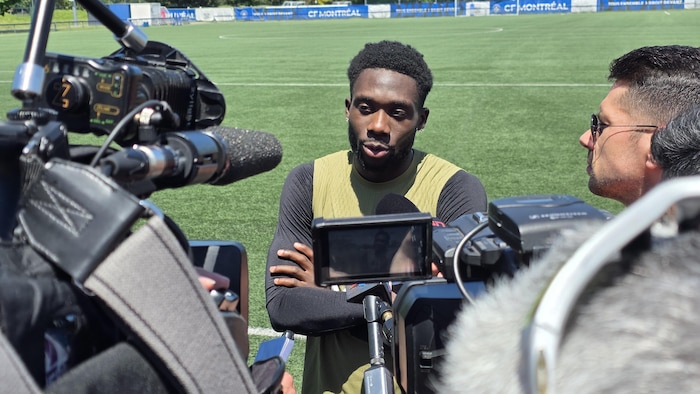 Un joueur de soccer parle devant des journalistes.