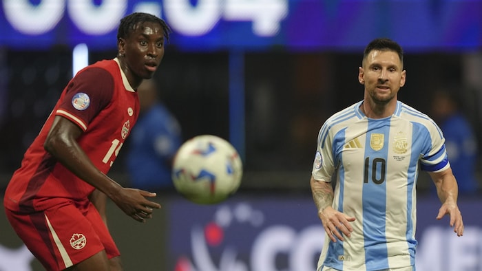 Deux joueurs de soccer regardent le ballon bondir.