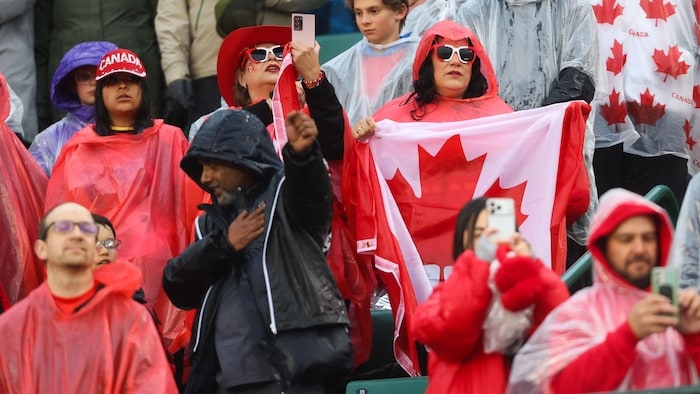 Des spectateurs dans les estrades avec des imperméables.