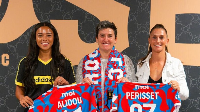 Trois femmes prennent la pose en tenant deux maillots de soccer.