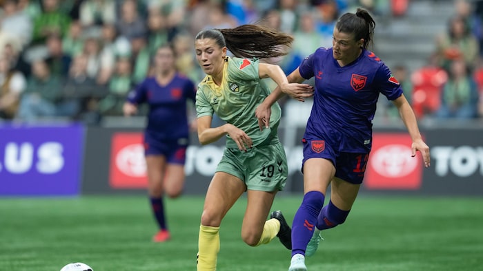 Elle court vers le ballon en tentant de se défaire d'une adversaire.