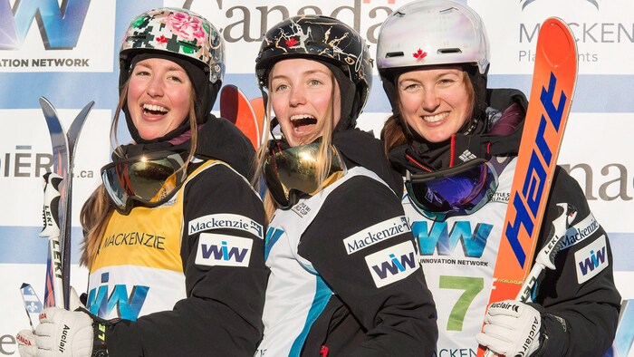 Trois skieuses sourient sur le podium.