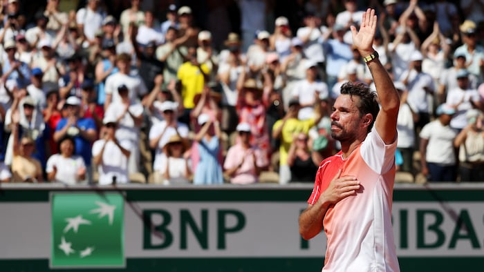 Un joueur de tennis salue la foule, une main sur le coeur. 