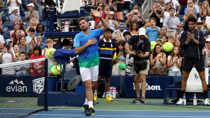 Un joueur de tennis salue la foule qui l'applaudit.