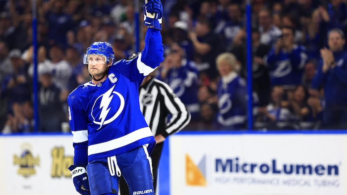 Un hockeyeur lève son bâton du bras gauche.