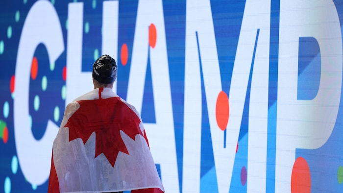 Elle marche avec un drapeau du Canada sur les épaules.