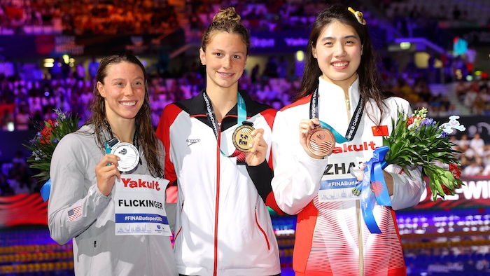 Trois athlètes sourient pour la photo et montrent leur médaille.