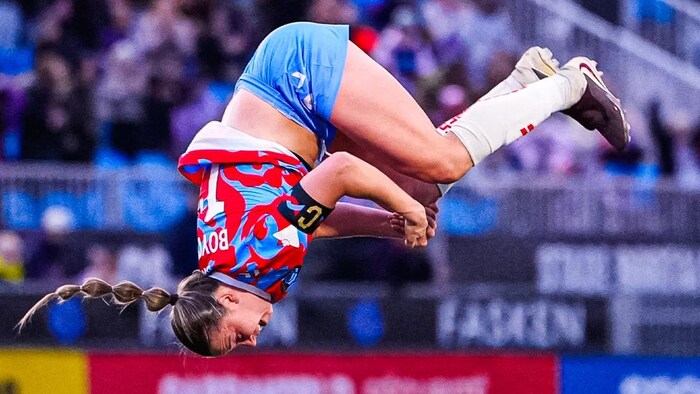 Une joueuse de soccer fait une pirouette à l'envers. 