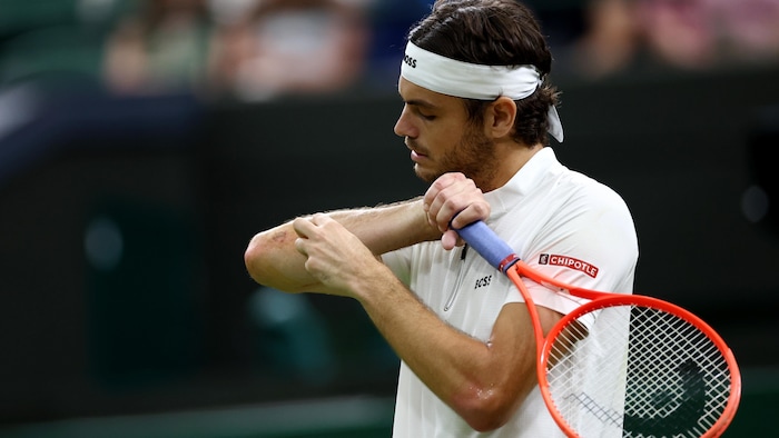 Un joueur de tennis se tient le coude droit.
