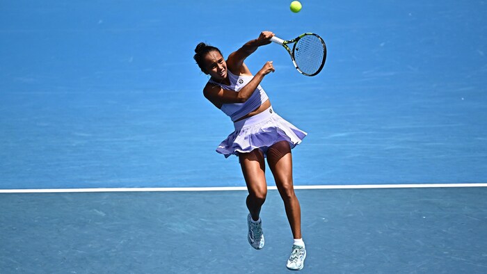 Une joueuse de tennis saute et frappe la balle.