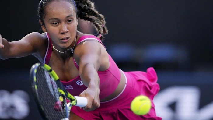 Une joueuse de tennis tente de frapper une balle du revers.