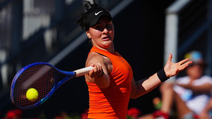 Une joueuse de tennis frappe une balle d'un coup droit.
