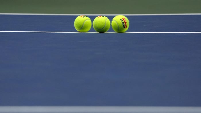 Trois balles sur un terrain de tennis bleu.