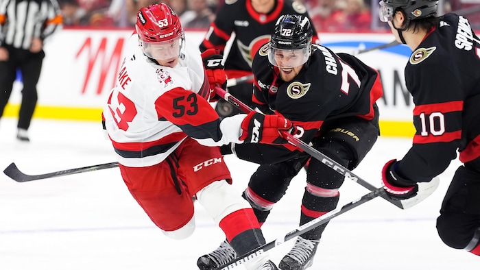 Un défenseur au hockey tente de stopper un adversaire pendant un match.