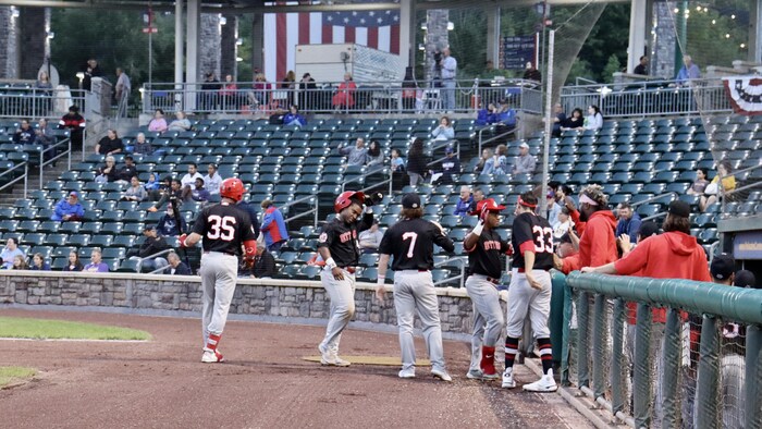 Un joueur de baseball est félicité par ses coéquipiers après avoir frappé un circuit.