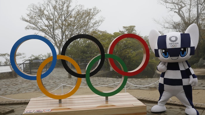 La mascota de los Juegos Olímpicos de Tokio posa junto a los anillos olímpicos.