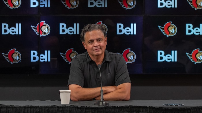 Un entraîneur de hockey parle aux journalistes.