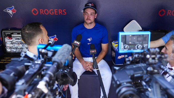 Il est entouré de journalistes, de caméras et de micro.