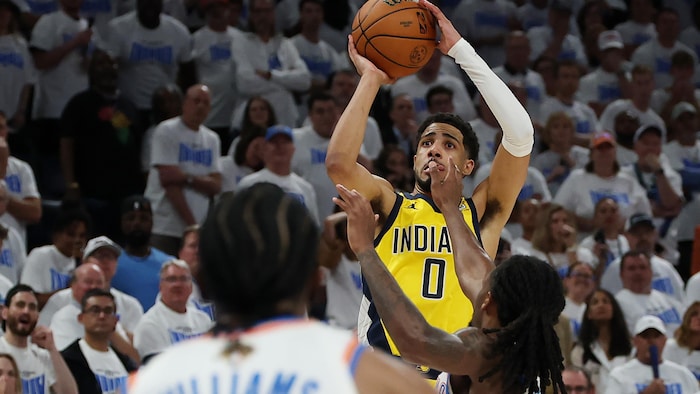 Un joueur en jaune lance un ballon de basketball.